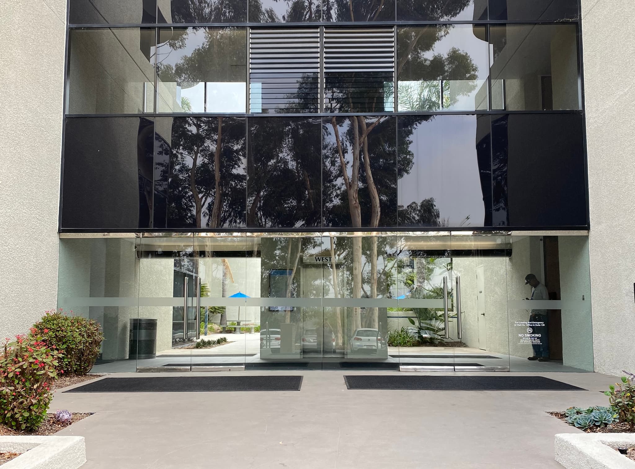 Building entrance at 7220 Trade Street, San Diego — a modernist glass-fronted commercial building