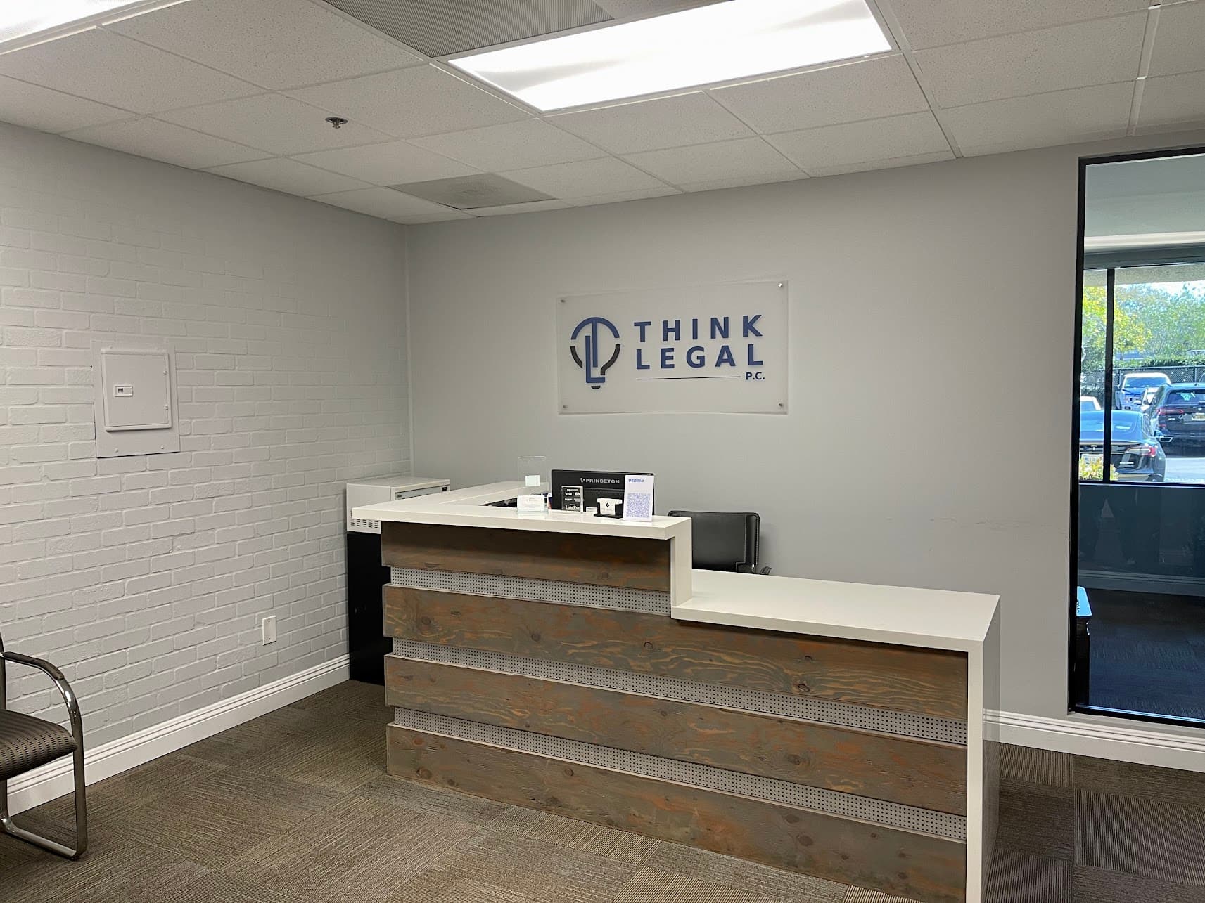 Reception area at Think Legal, P.C., showing the firm's brand sign and wood-front reception desk